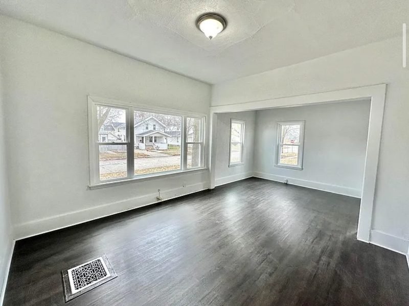 The same living room after the work: white walls, new dark wood floors