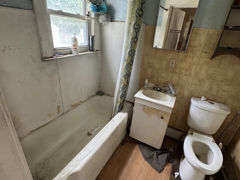 Bathroom before: stained tub, old fixtures and peeling paint