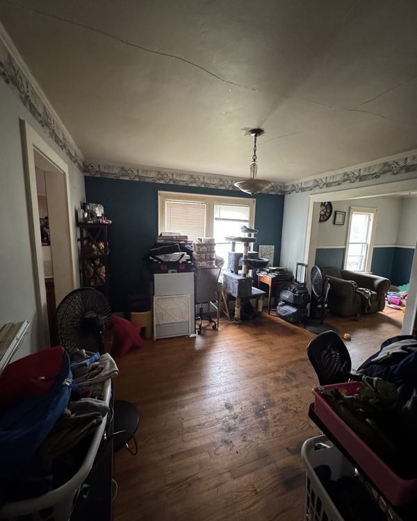 Living room with dark blue walls and furniture and belongings throughout, as found