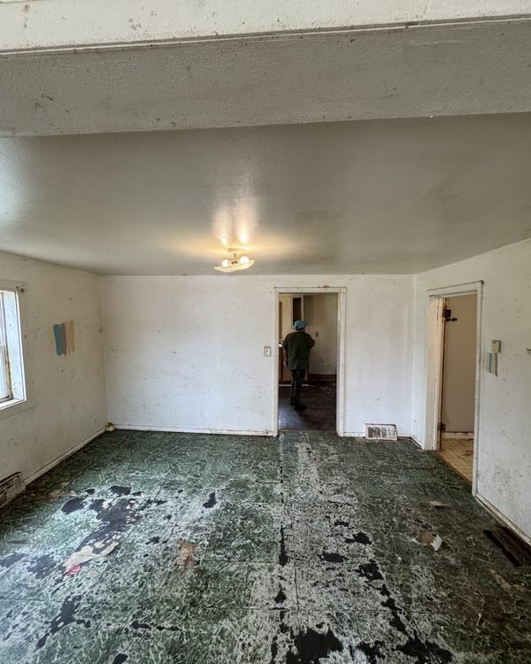 Empty room with a badly worn painted floor covered in debris, as found