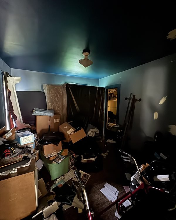 Bedroom full of boxes, furniture and belongings left behind, as found