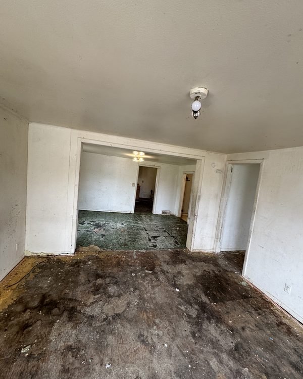 Empty room with a dark, water-damaged floor, as found
